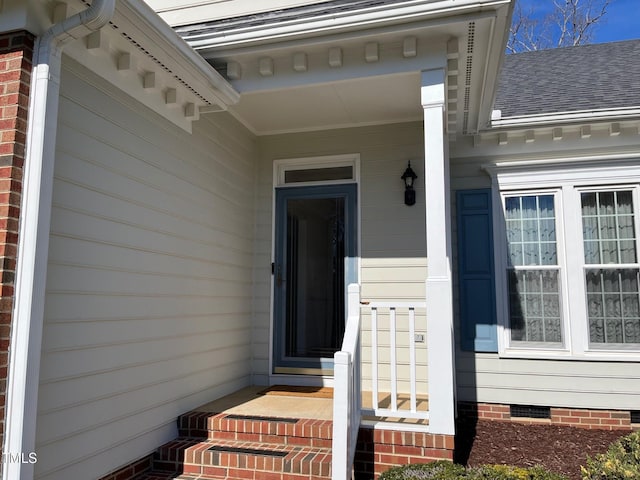 property entrance featuring crawl space, a shingled roof, and brick siding