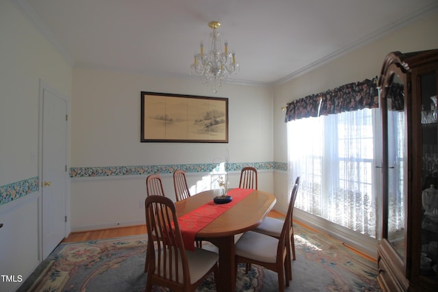 dining room with a notable chandelier, crown molding, and light wood finished floors