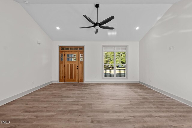 unfurnished living room with ceiling fan, vaulted ceiling, and light wood-type flooring