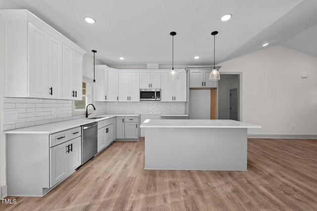 kitchen with appliances with stainless steel finishes, a center island, white cabinetry, and pendant lighting