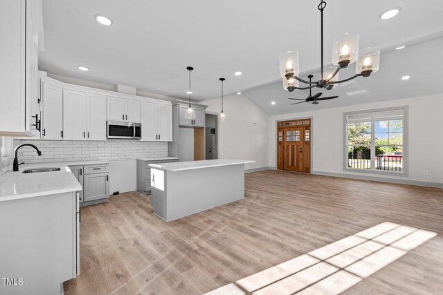 kitchen featuring pendant lighting, a kitchen island, white cabinetry, and sink