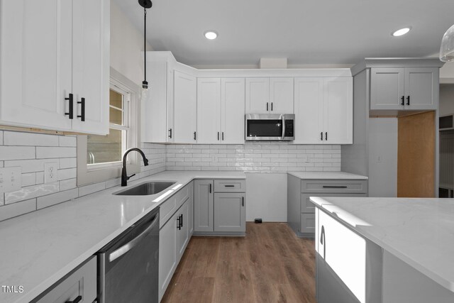 kitchen featuring appliances with stainless steel finishes, light stone counters, pendant lighting, and sink