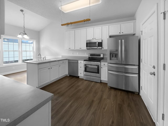 kitchen featuring pendant lighting, white cabinets, a textured ceiling, kitchen peninsula, and stainless steel appliances