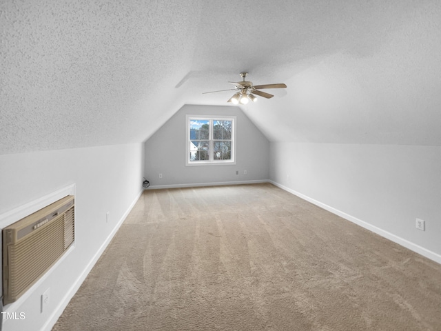 bonus room featuring ceiling fan, an AC wall unit, carpet floors, a textured ceiling, and vaulted ceiling