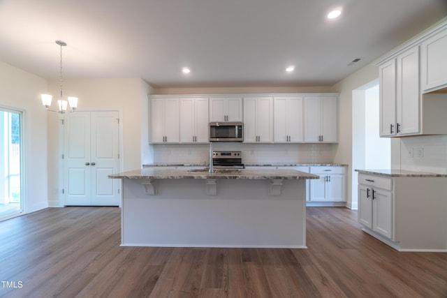 kitchen featuring stainless steel appliances, white cabinetry, and a kitchen island with sink