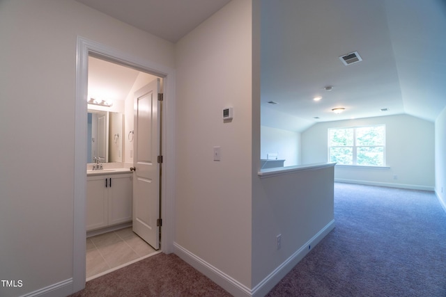 hallway featuring light carpet, lofted ceiling, and sink