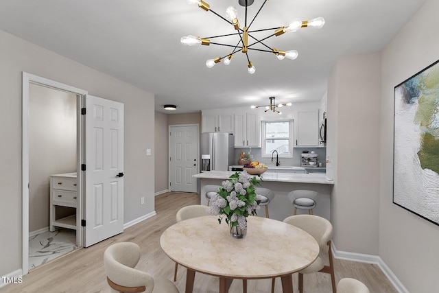 dining room with light hardwood / wood-style flooring, a chandelier, and sink