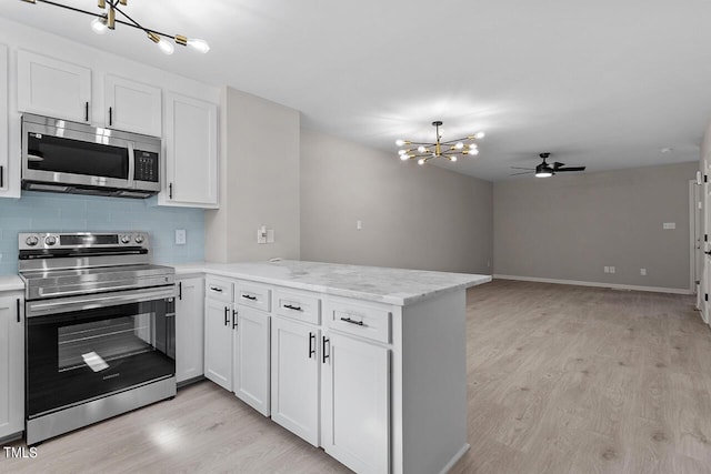 kitchen featuring white cabinets, ceiling fan with notable chandelier, decorative backsplash, appliances with stainless steel finishes, and kitchen peninsula