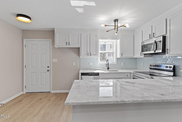 kitchen with light stone counters, sink, white cabinets, and appliances with stainless steel finishes