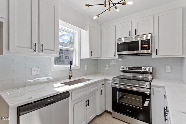 kitchen with white cabinets, stainless steel appliances, light stone countertops, and sink