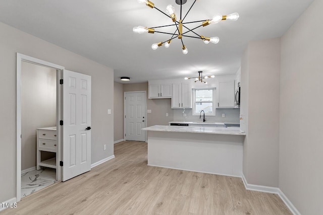 kitchen with white cabinetry, sink, kitchen peninsula, pendant lighting, and a chandelier