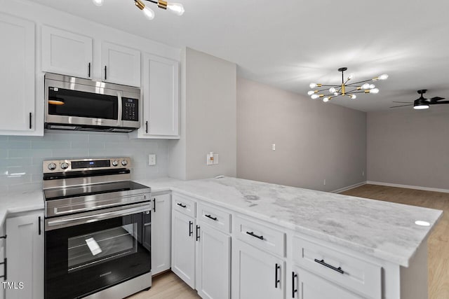 kitchen with kitchen peninsula, appliances with stainless steel finishes, white cabinets, and decorative backsplash