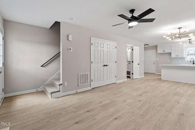 unfurnished living room featuring light hardwood / wood-style floors and ceiling fan with notable chandelier