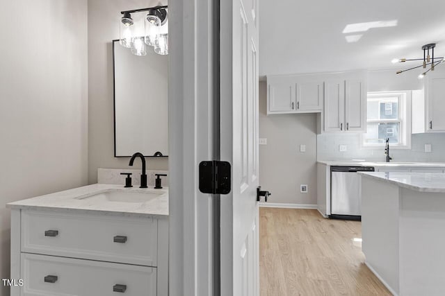 bathroom featuring backsplash, sink, an inviting chandelier, and hardwood / wood-style flooring