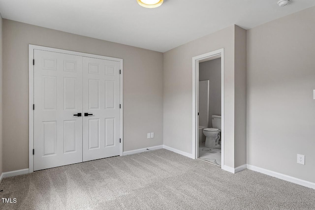 unfurnished bedroom featuring carpet, a closet, and ensuite bath