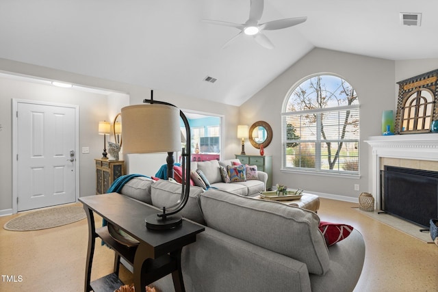 living room featuring ceiling fan, a tile fireplace, and vaulted ceiling