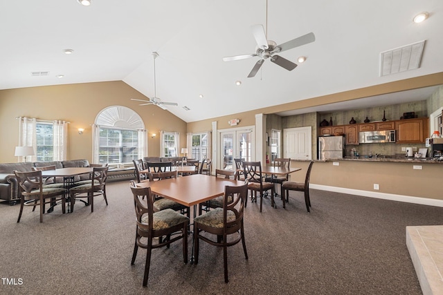 carpeted dining space with ceiling fan and high vaulted ceiling