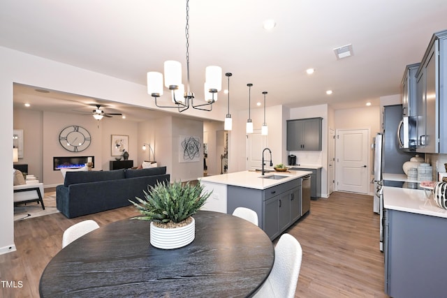 dining area featuring sink, ceiling fan with notable chandelier, and hardwood / wood-style floors