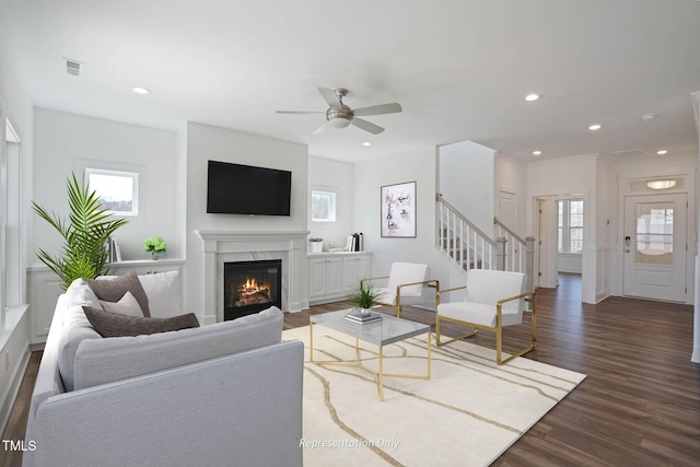 living room featuring a premium fireplace, ceiling fan, and dark wood-type flooring