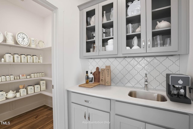 bar featuring gray cabinetry, decorative backsplash, dark hardwood / wood-style flooring, and sink