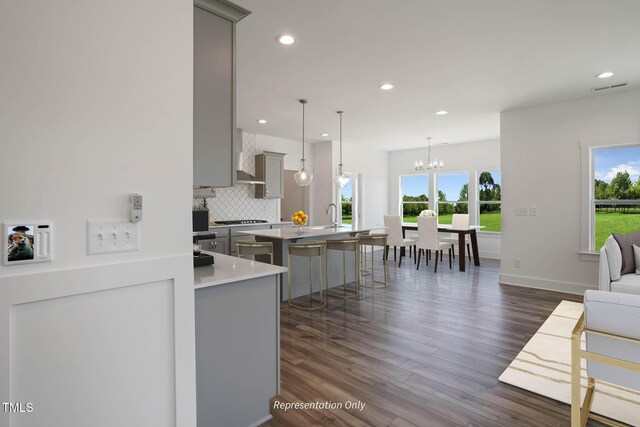 kitchen featuring pendant lighting, a kitchen bar, backsplash, and a wealth of natural light