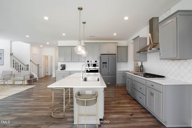 kitchen with gray cabinetry, wall chimney exhaust hood, and stainless steel appliances