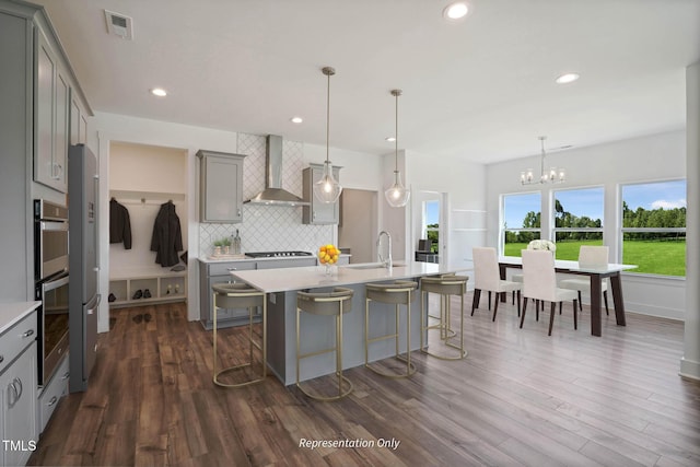 kitchen featuring pendant lighting, sink, gray cabinetry, and wall chimney range hood