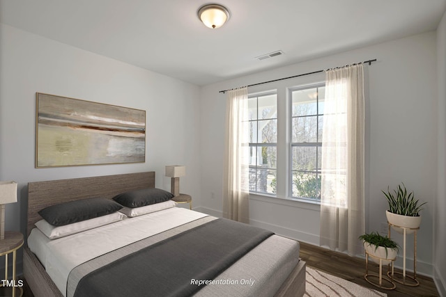 bedroom with multiple windows and dark hardwood / wood-style flooring