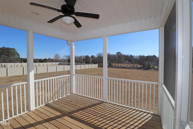 unfurnished sunroom featuring a rural view and ceiling fan