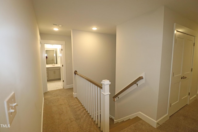 corridor featuring light carpet and sink