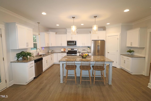 kitchen with white cabinets, a kitchen island, hanging light fixtures, and appliances with stainless steel finishes