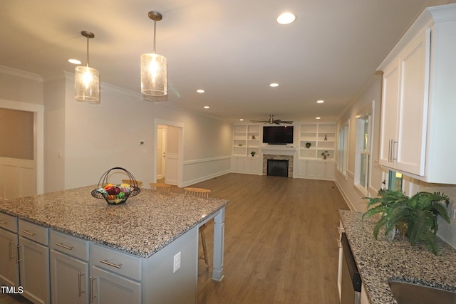 kitchen with ceiling fan, built in features, a breakfast bar, white cabinets, and ornamental molding