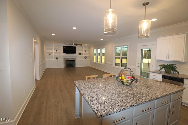 kitchen with white cabinetry, a center island, ceiling fan, hanging light fixtures, and stainless steel dishwasher