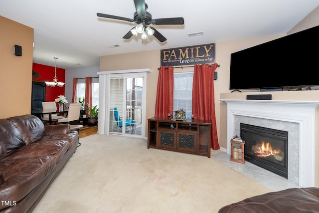 carpeted living room with ceiling fan with notable chandelier