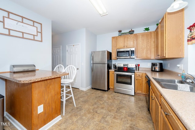 kitchen featuring stainless steel appliances, kitchen peninsula, sink, and a breakfast bar area