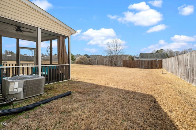 view of yard featuring a sunroom, central AC, and ceiling fan