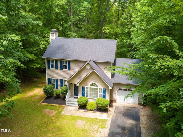 colonial inspired home with covered porch, a garage, and a front yard