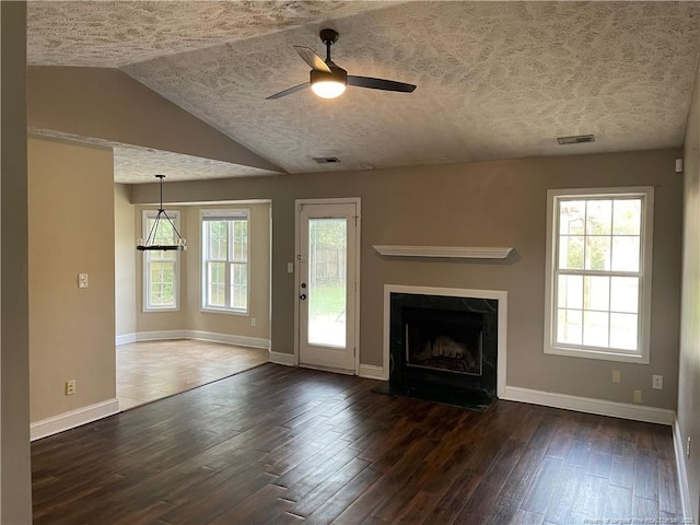 unfurnished living room with dark hardwood / wood-style flooring, a textured ceiling, ceiling fan, a fireplace, and lofted ceiling