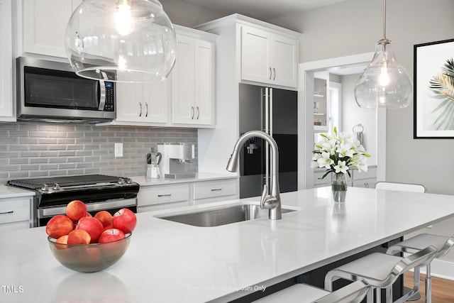 kitchen with a kitchen bar, sink, white cabinets, and appliances with stainless steel finishes