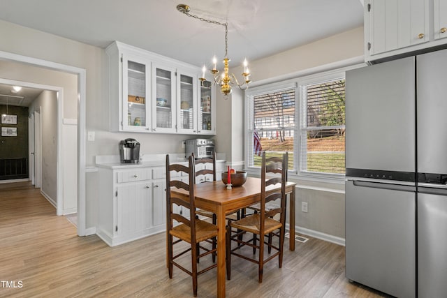 dining space with light hardwood / wood-style floors and an inviting chandelier