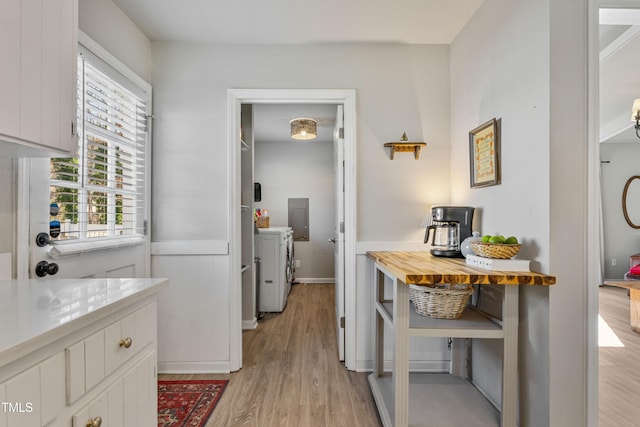 kitchen featuring a healthy amount of sunlight, washing machine and dryer, white cabinetry, and light hardwood / wood-style flooring