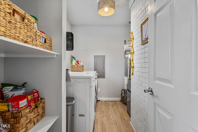 washroom featuring washer and dryer, electric panel, light hardwood / wood-style floors, and gas water heater