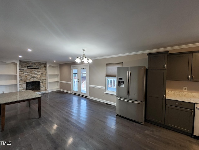 kitchen with light stone countertops, stainless steel fridge, ornamental molding, built in shelves, and a fireplace