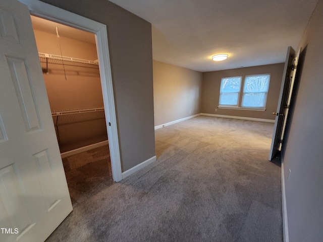 unfurnished bedroom with carpet, a spacious closet, and a closet