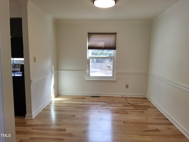 unfurnished room featuring crown molding and light wood-type flooring