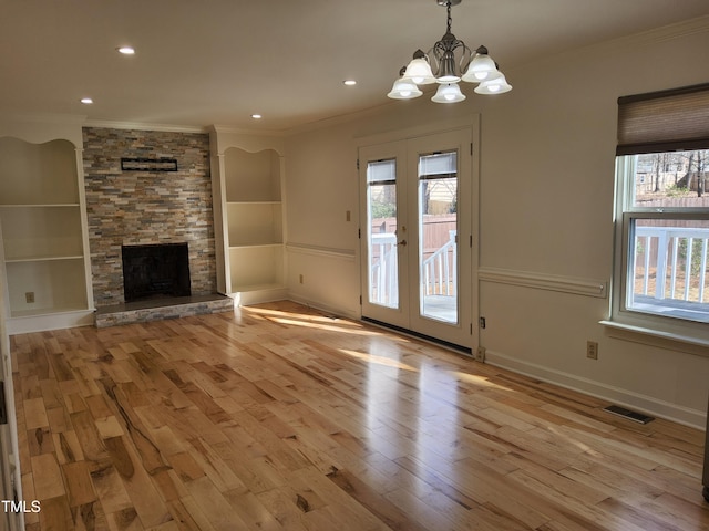 unfurnished living room with a stone fireplace, light hardwood / wood-style flooring, french doors, and plenty of natural light