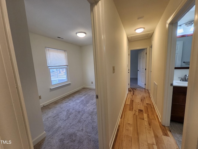 hallway with sink and light hardwood / wood-style floors