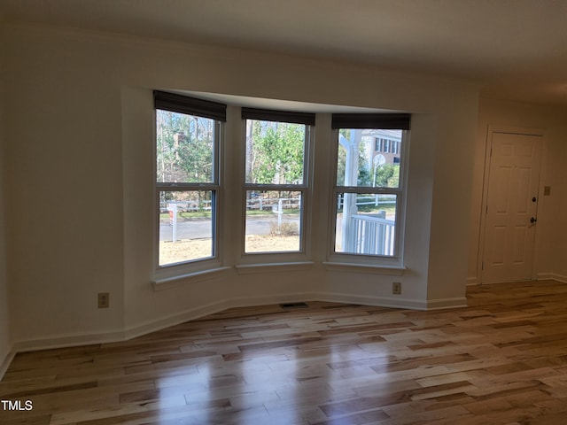 spare room featuring crown molding and light hardwood / wood-style floors