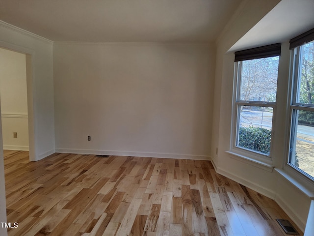 empty room with ornamental molding and light hardwood / wood-style flooring