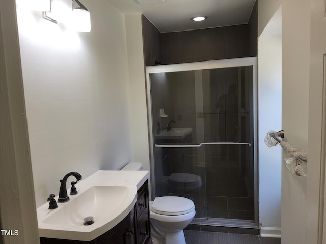 bathroom featuring vanity, a shower with shower door, and toilet